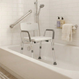 A durable white plastic shower chair with height-adjustable metal legs, non-slip rubber feet, armrests, and a backrest sits inside a white bathtub next to a grab bar.