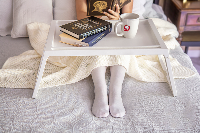 Woman on bed wearing white compression stockings