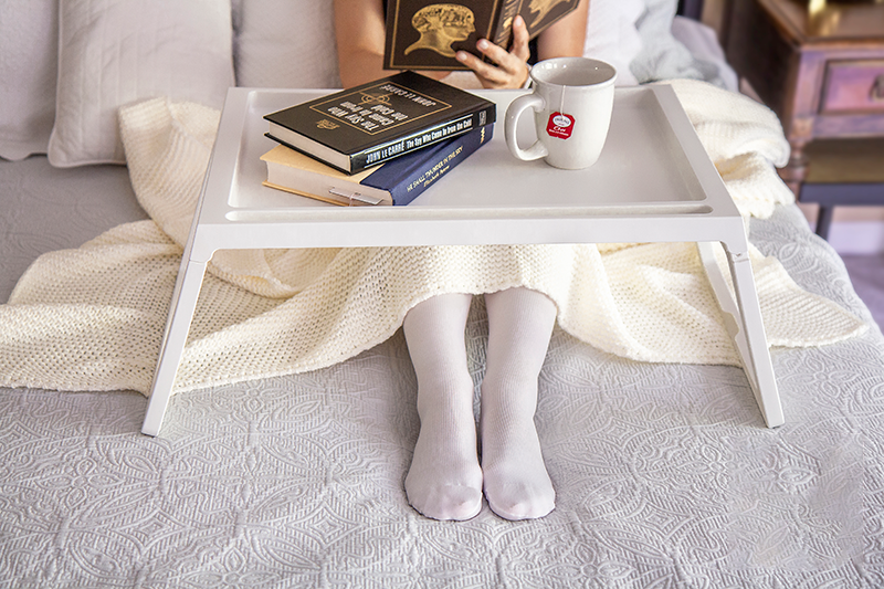 Woman on bed wearing white compression stockings 