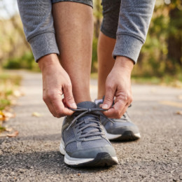 Close-up of a person tying athletic shoes on an outdoor trail, illustrating comfortable everyday mobility following Binson's update on Diabetic Footwear services.