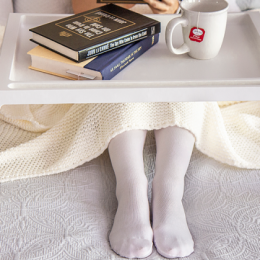 Woman on bed wearing white compression stockings