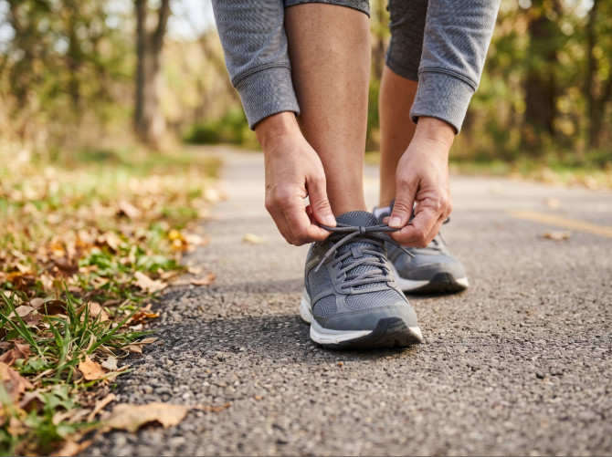 Close-up of a person tying athletic shoes on an outdoor trail, illustrating comfortable everyday mobility following Binson's update on Diabetic Footwear services.
