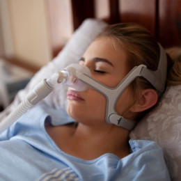 A calm woman sleeping with a CPAP mask, showcasing comfortable sleep apnea therapy.