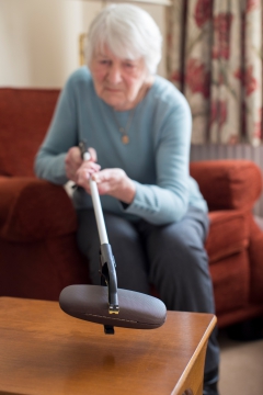 Person using a reacher to grab glasses from a table