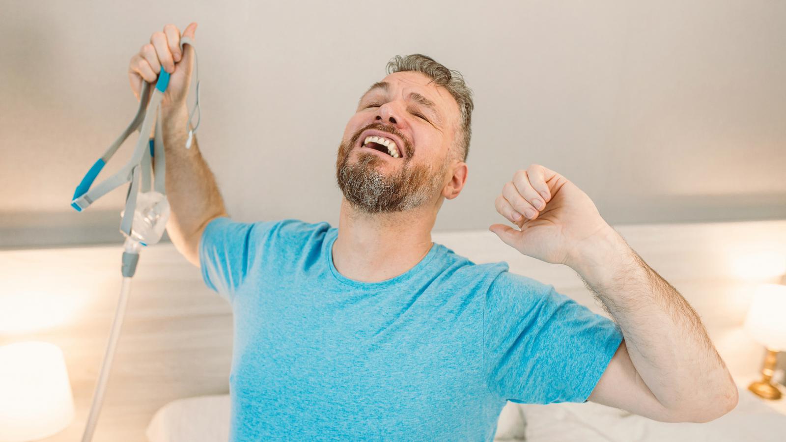 Man holding CPAP mask looking well rested