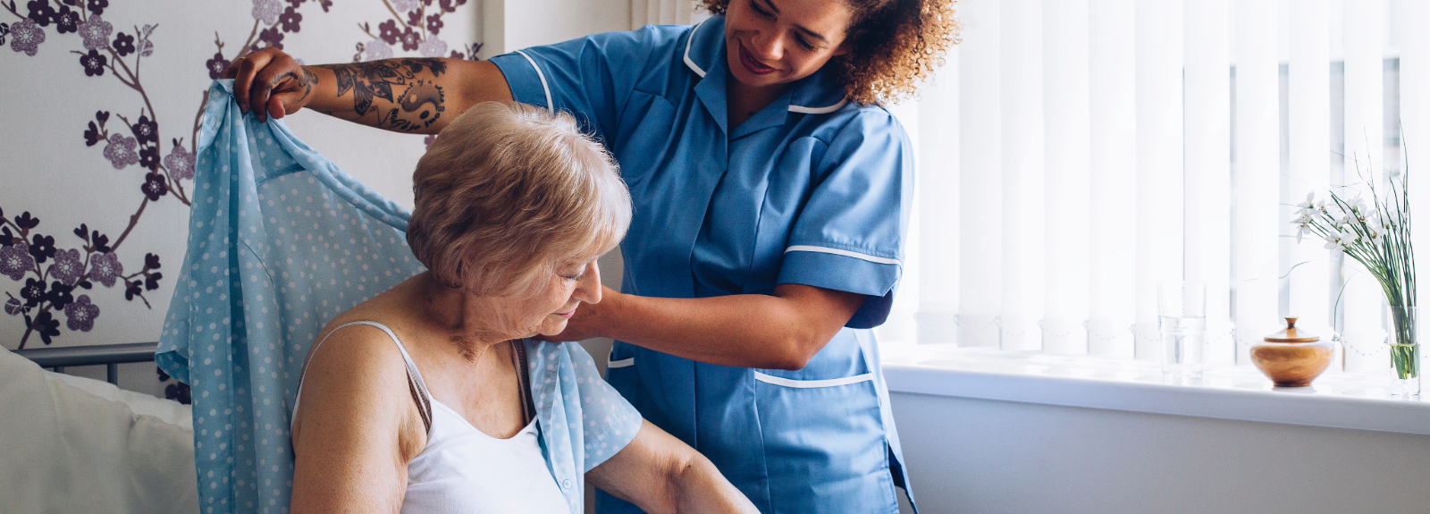 Home nurse helping patient get dressed in bed