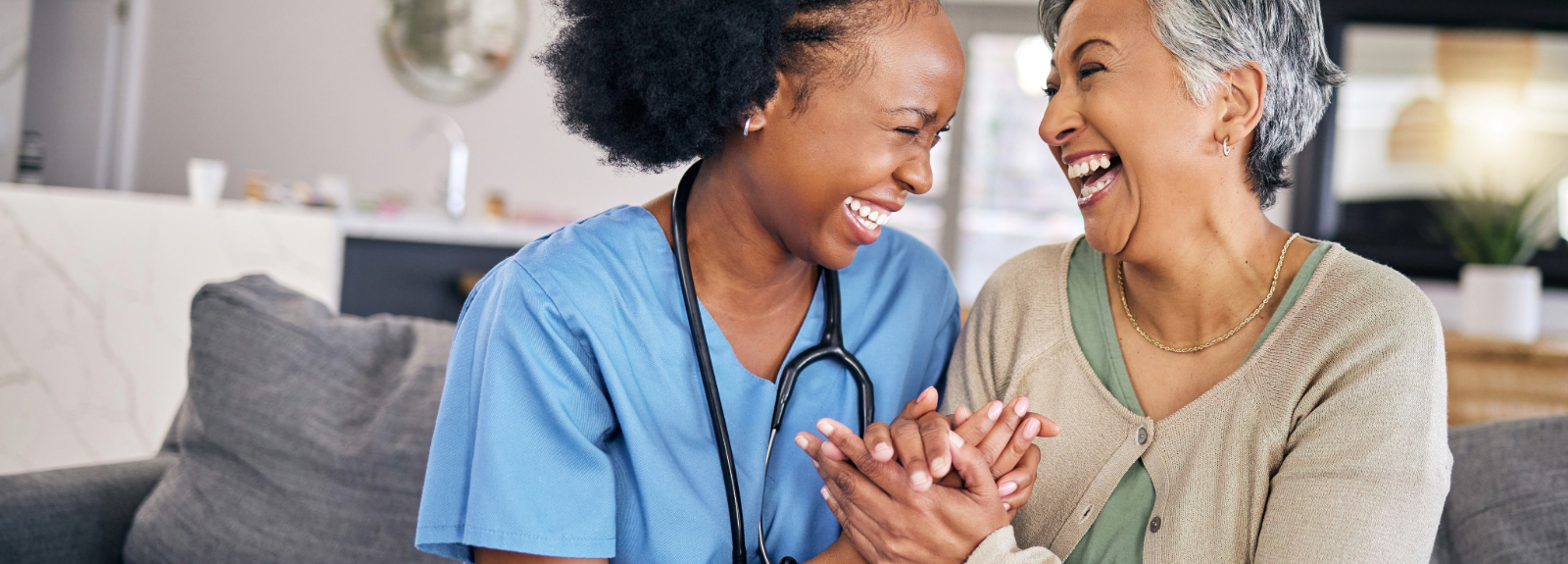 Home nurse holding hands and smiling with elderly patient in their home