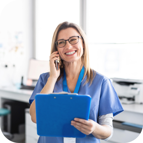 Nurse smiling and talking on the phone holding a clipboard.