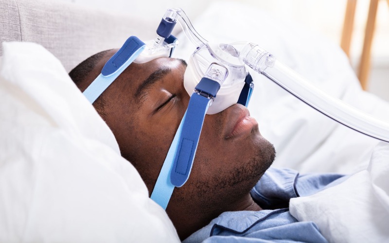 Person wearing a cpap mask while sleeping in bed