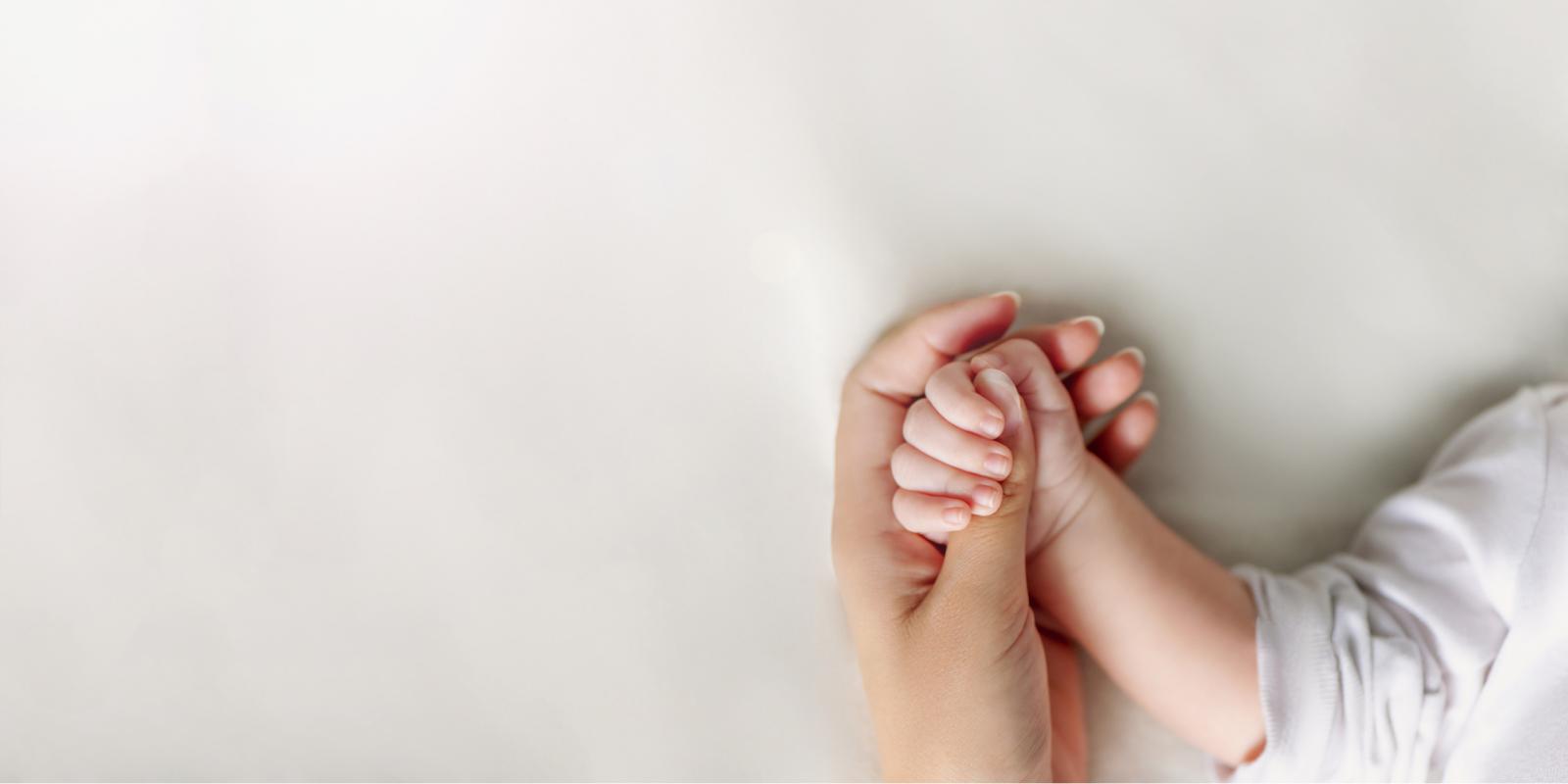 Woman holding hands with an infant