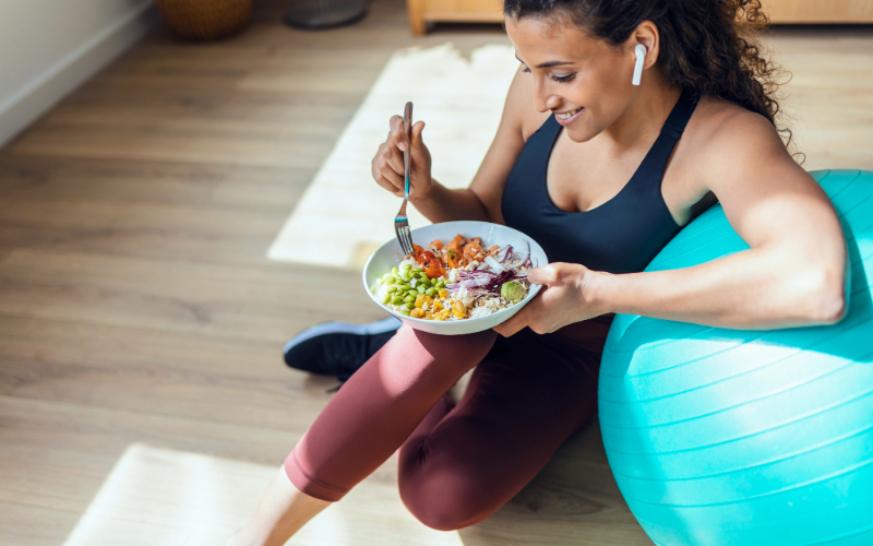 Person eating a bowl of food sitting near exercise equipment