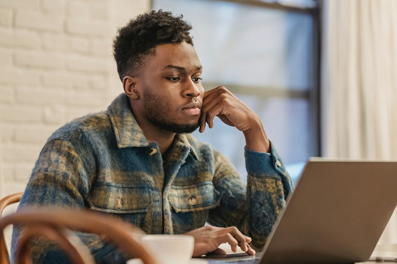 Man sitting at a desk thinking looking at computer Photo by Andres Ayrton from Pexels