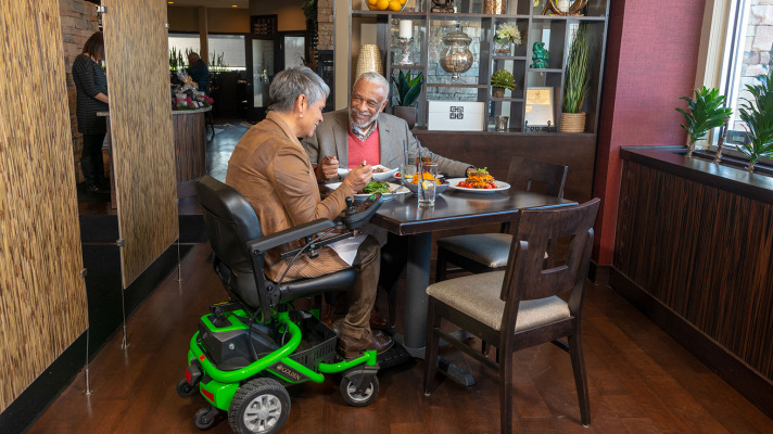 Woman in Golden Tech power weelchair at restaurant 