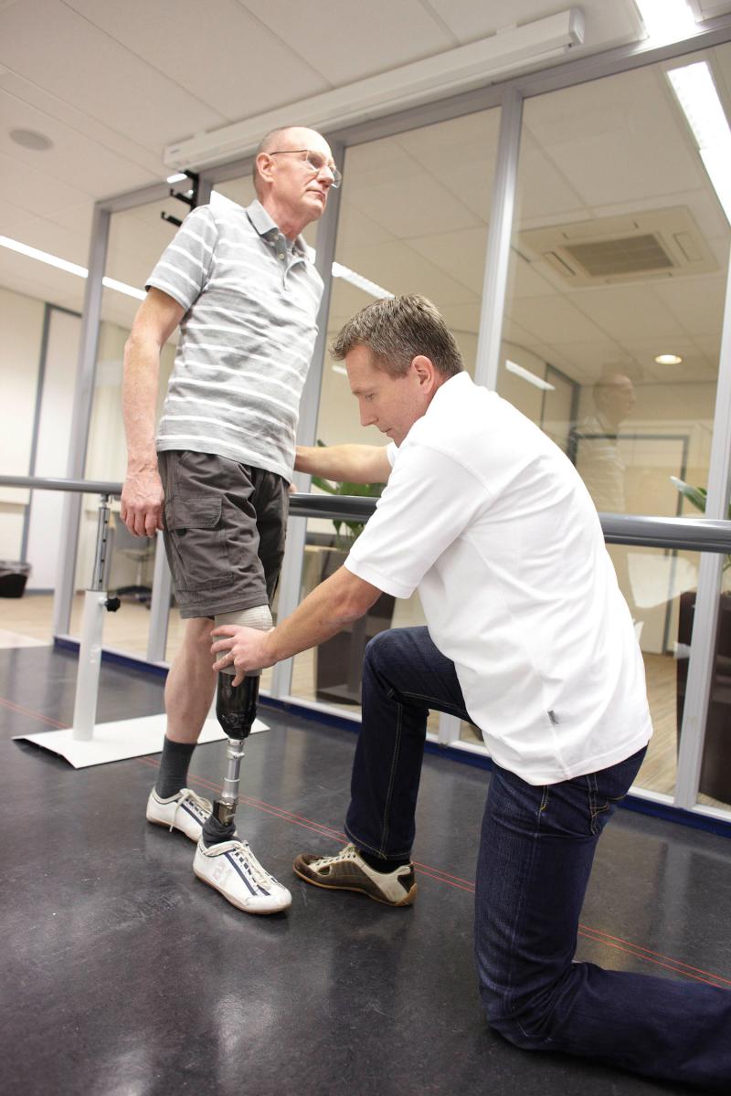 Clinician adjusting man's prosthetic leg