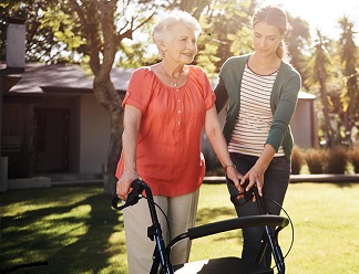 Woman walking with walker and caregiver